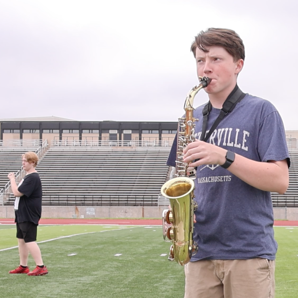  A student practices saxophone on a football field